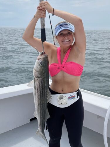Girl holding a large striped bass on a hook