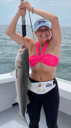 Girl holding a large striped bass on a hook